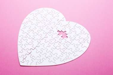 Pembe bir arka plan üzerinde beyaz bulmaca kalp. Eksik parça. Üstten görünüm