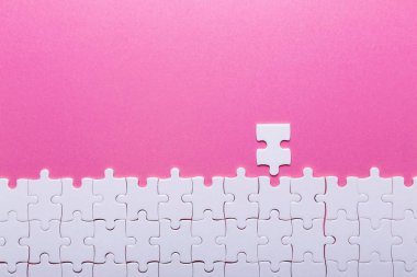 Pembe arka planda beyaz bulmaca. Kayıp parça. Üst görünüm