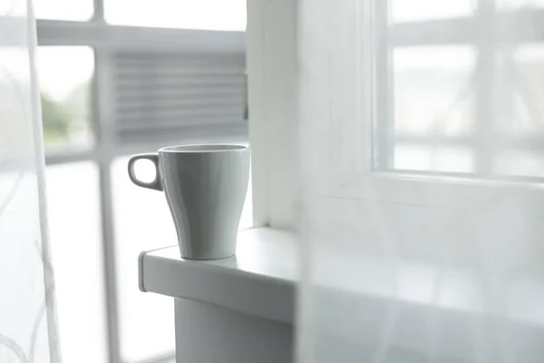 A cup of coffee on the windowsill. Big window. Scandinavian style. Copy space