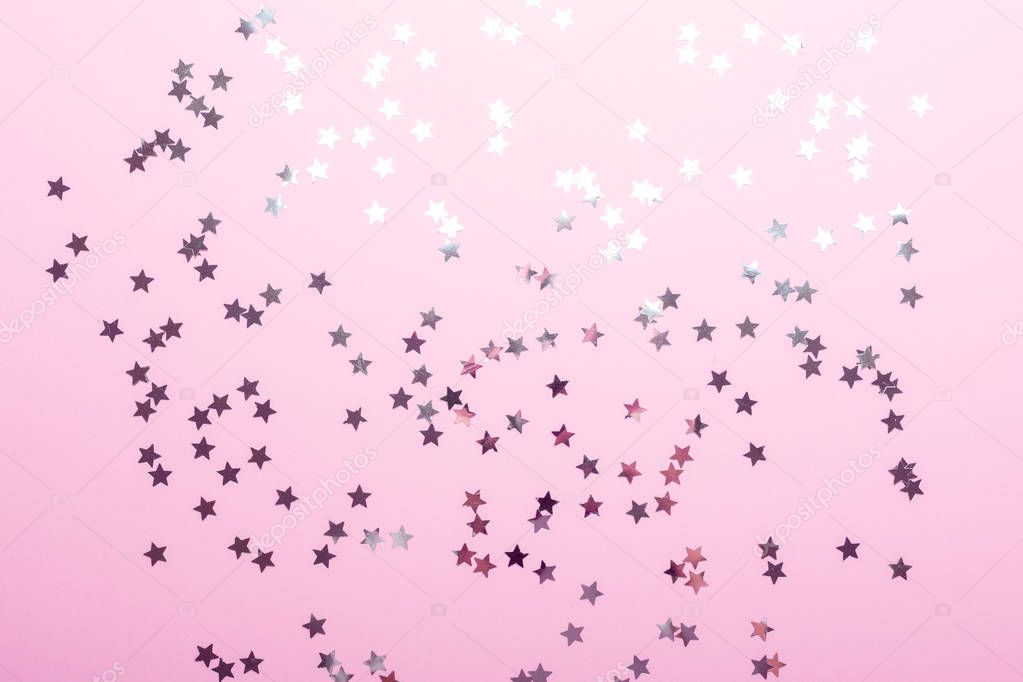 Pink background with silver star confetti. Top view. Copy space.