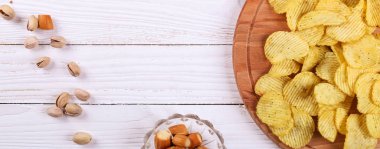 Beyaz ahşap bir masa Snacks. Cips, Antep fıstığı, Kuru peynir. Üstten görünüm