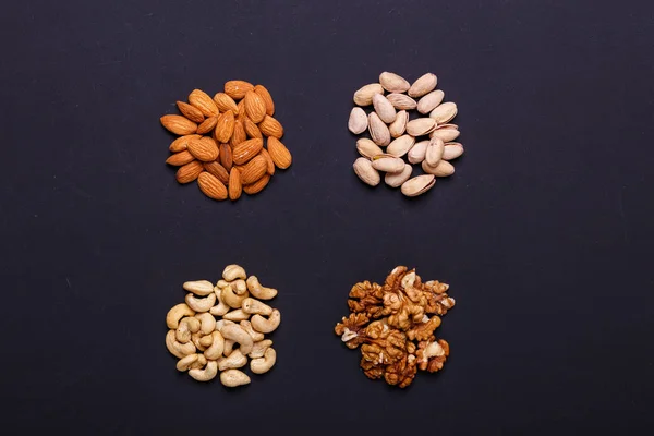 Assortment of nuts on a black background - healthy snack. Top view. Copy space