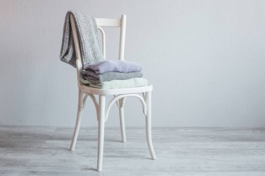 Bir tahta sandalyede rahat örme elbise yığını. Gri duvar. Vintage renklendirme