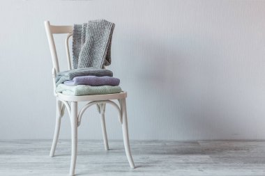 Bir tahta sandalyede rahat örme elbise yığını. Gri duvar. Vintage renklendirme