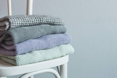 Bir tahta sandalyede rahat örme elbise yığını. Gri duvar. Vintage renklendirme