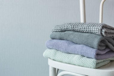 Bir tahta sandalyede rahat örme elbise yığını. Gri duvar. Vintage renklendirme