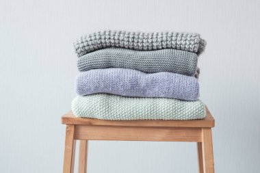 Ahşap merdiven rahat örme elbise yığını. Gri duvar. Vintage renklendirme