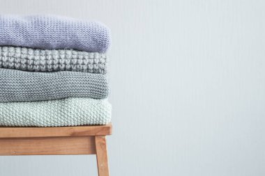 Ahşap merdiven rahat örme elbise yığını. Gri duvar. Vintage renklendirme