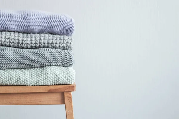 Ahşap merdiven rahat örme elbise yığını. Gri duvar. Vintage renklendirme