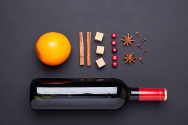 Bir şişe kırmızı şarap ve baharat için siyah arka plan üzerinde mulled şarap. Tarçın, anason, turuncu, kahverengi şeker, kızılcık yıldız. Üstten görünüm.