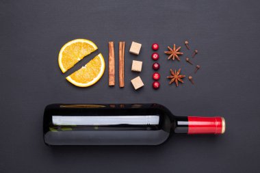 Bir şişe kırmızı şarap ve baharat için siyah arka plan üzerinde mulled şarap. Tarçın, anason, turuncu, kahverengi şeker, kızılcık yıldız. Üstten görünüm.