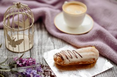 Bir fincan sıcak kahve, pasta ve çiçekler rustik ahşap masa, closeup fotoğraf sıcak kazak, kış sabah kavramı, üstten görünüm. Renkli vintage