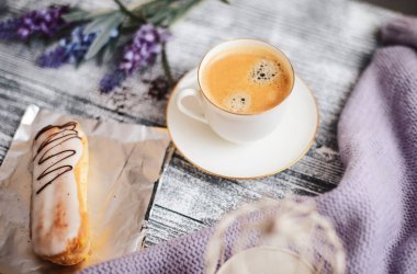 Bir fincan sıcak kahve, pasta ve çiçekler rustik ahşap masa, closeup fotoğraf sıcak kazak, kış sabah kavramı, üstten görünüm. Renkli vintage
