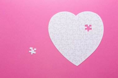 Pembe bir arka plan üzerinde beyaz bulmaca kalp. Üstten görünüm