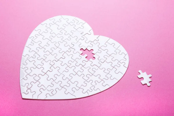 Witte puzzel hart op roze achtergrond. Bovenaanzicht — Stockfoto