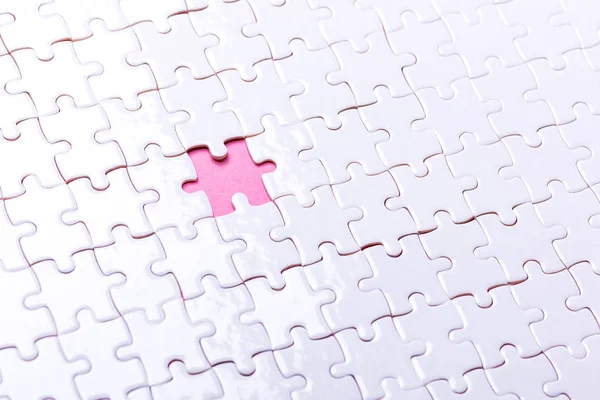 Weißes Puzzle auf rosa Hintergrund. Ansicht von oben — Stockfoto