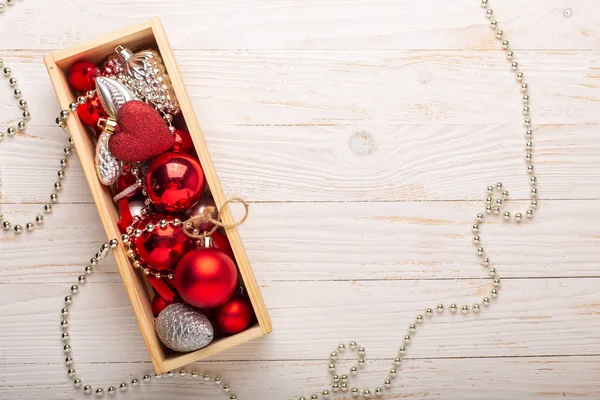 Box with silver and red christmas gifts on white wooden background. Top view. Copy space