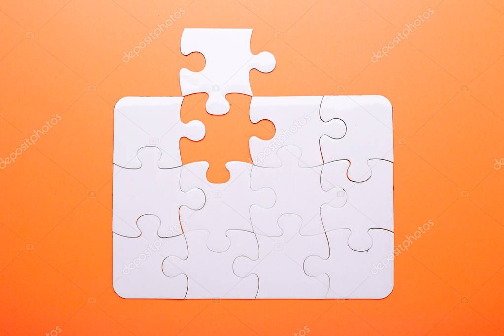 White puzzle on orange background. Missing piece. Top view