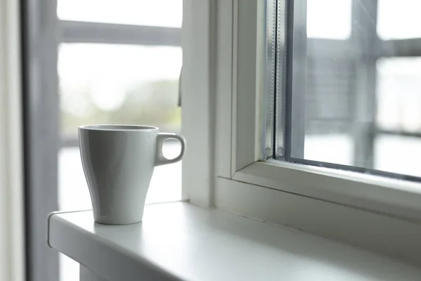 A cup of coffee on the windowsill. Big window. Scandinavian style. Copy space
