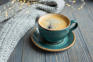 Bir fincan kahve, sıcak örme kazak ahşap arka plan üzerine. Sıcak ışıklar. Kış sabahı rahat. Yaşam tarzı kavramı. Seçici odak.