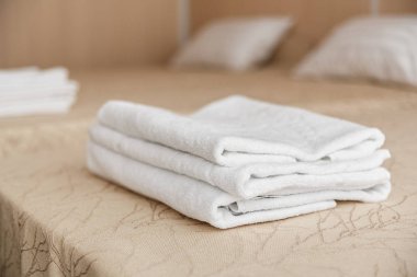 Yatakta otelde beyaz otel havlu yığını. Yumuşak odak.