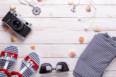 Tatil kavramı sandalet, kulaklık, güneş gözlüğü, kamera, kabukları ve çizgili tişört ile seyahat. Üstten görünüm kopya alanı ile. Düz yatıyordu