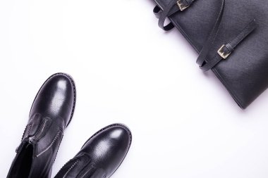 Kadın aksesuar. Beyaz arka planda siyah şık çizmeler, siyah lüks deri çanta. Üstten görünüm arka plan. Düz yatıyordu. Kopya alanı.