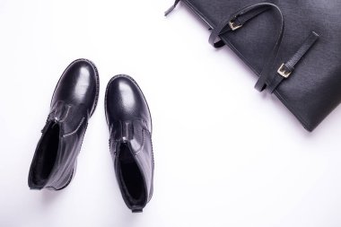 Kadın aksesuar. Beyaz arka planda siyah şık çizmeler, siyah lüks deri çanta. Üstten görünüm arka plan. Düz yatıyordu. Kopya alanı.