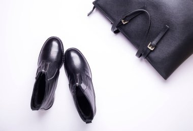 Kadın aksesuar. Beyaz arka planda siyah şık çizmeler, siyah lüks deri çanta. Üstten görünüm arka plan. Düz yatıyordu. Kopya alanı.