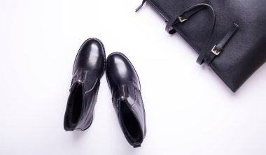 Kadın aksesuar. Beyaz arka planda siyah şık çizmeler, siyah lüks deri çanta. Üstten görünüm arka plan. Düz yatıyordu. Kopya alanı.