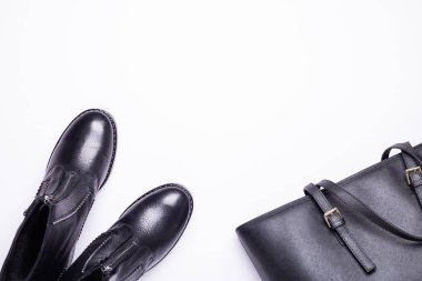 Kadın aksesuar. Beyaz arka planda siyah şık çizmeler, siyah lüks deri çanta. Üstten görünüm arka plan. Düz yatıyordu. Kopya alanı.