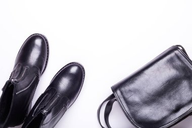 Kadın aksesuar. Beyaz arka planda siyah şık çizmeler, siyah lüks deri çanta. Üstten görünüm arka plan. Düz yatıyordu. Kopya alanı.