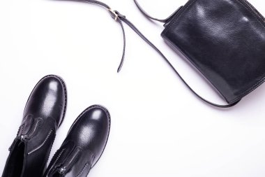 Kadın aksesuar. Beyaz arka planda siyah şık çizmeler, siyah lüks deri çanta. Üstten görünüm arka plan. Düz yatıyordu. Kopya alanı.