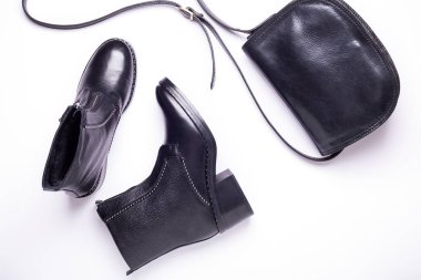 Kadın aksesuar. Beyaz arka planda siyah şık çizmeler, siyah lüks deri çanta. Üstten görünüm arka plan. Düz yatıyordu. Kopya alanı.