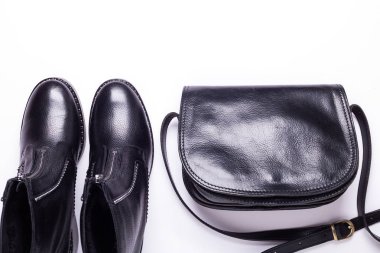 Kadın aksesuar. Beyaz arka planda siyah şık çizmeler, siyah lüks deri çanta. Üstten görünüm arka plan. Düz yatıyordu. Kopya alanı.