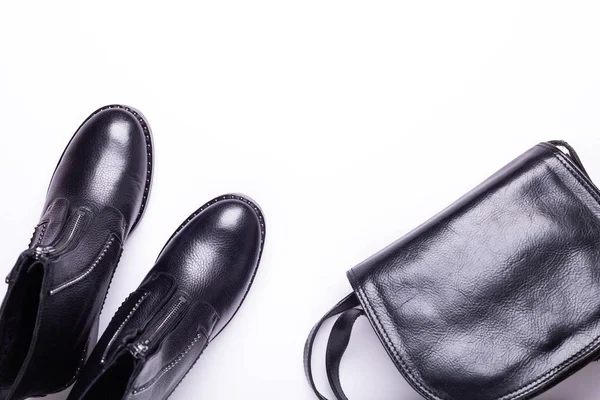 Kadın aksesuar. Beyaz arka planda siyah şık çizmeler, siyah lüks deri çanta. Üstten görünüm arka plan. Düz yatıyordu. Kopya alanı.