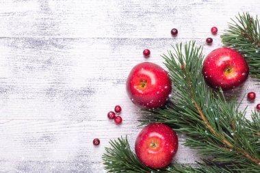 Noel arka plan ağaç dalları, kırmızı elma ve cranberries ile. Ahşap masa lambası. Kar yağışı çizim efekti. Üstten görünüm. Kopya alanı