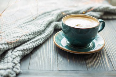 Bir fincan kahve, sıcak örme kazak ahşap arka plan üzerine. Sıcak ışıklar. Kış sabahı rahat. Yaşam tarzı kavramı. Seçici odak.