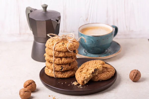 Cup of coffee, oatmeal cookies, coffee maker on white wooden background. Bright morning