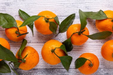 Taze portakal mandalina mandalina Beyaz ahşap zemin üzerine yeşil yaprakları ile. Üstten görünüm