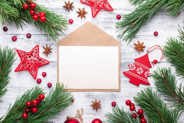 Fir branches, gifts and an envelope on a light wooden background. Cranberries, spices, holly berries. Christmas background. Flat lay, top view, copy space.