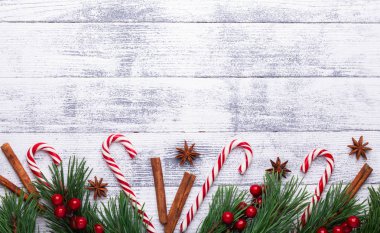 Noel arka plan. Çam dalları, şeker kamışı ve hediyeler hafif ahşap arka plan üzerinde. Kızılcık, baharat, holly Karpuzu. Düz yatıyordu, en iyi görünüm, kopya alanı.