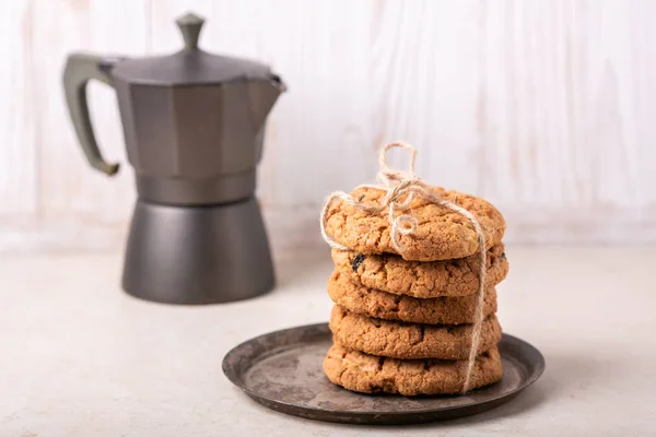 Stack of oatmeal cookies, coffee maker on white wooden background Homemade bakery Healthy food snack concept