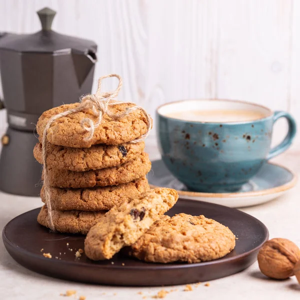 Cup of coffee, stack of oatmeal cookies, coffee maker on white wooden background Homemade bakery Healthy food snack concept