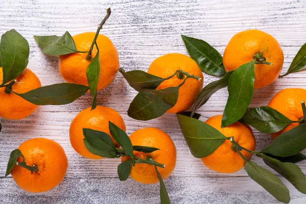 新鮮なオレンジ色のマンダリン タンジェリン 白い木製の背景に緑の葉 トップ ビュー — ストック写真