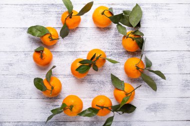 Taze portakal mandalina mandalina Beyaz ahşap zemin üzerine yeşil yaprakları ile. Üstten görünüm. Kopya alanı