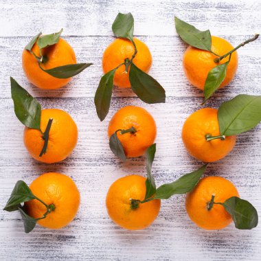 Taze portakal mandalina mandalina Beyaz ahşap zemin üzerine yeşil yaprakları ile. Üstten görünüm