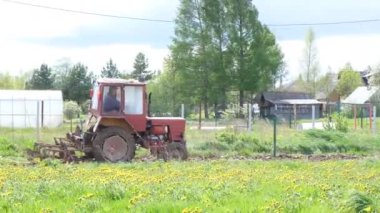 Küçük bir traktör tarladaki araziyi sürüyor. Kırsal alan. 4k görüntü