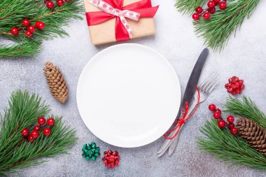 Boş beyaz tabak, hediye kutusu, süslü süslemeli çatal bıçak seti taştan arka planda yıldız yay topu. Noel ve Yeni Yıl Tatil Konsepti - Görüntü