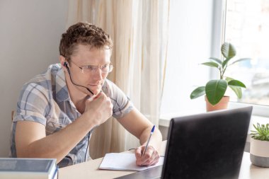 Programcı evden, uzaktan kumandalı, ev ofisinden çalışıyor. Gözlüklü bir adam monitöre bakıyor. Uzak çalışma konsepti - Resim